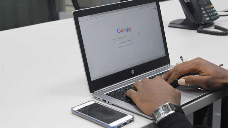 man typing in Google on his laptop